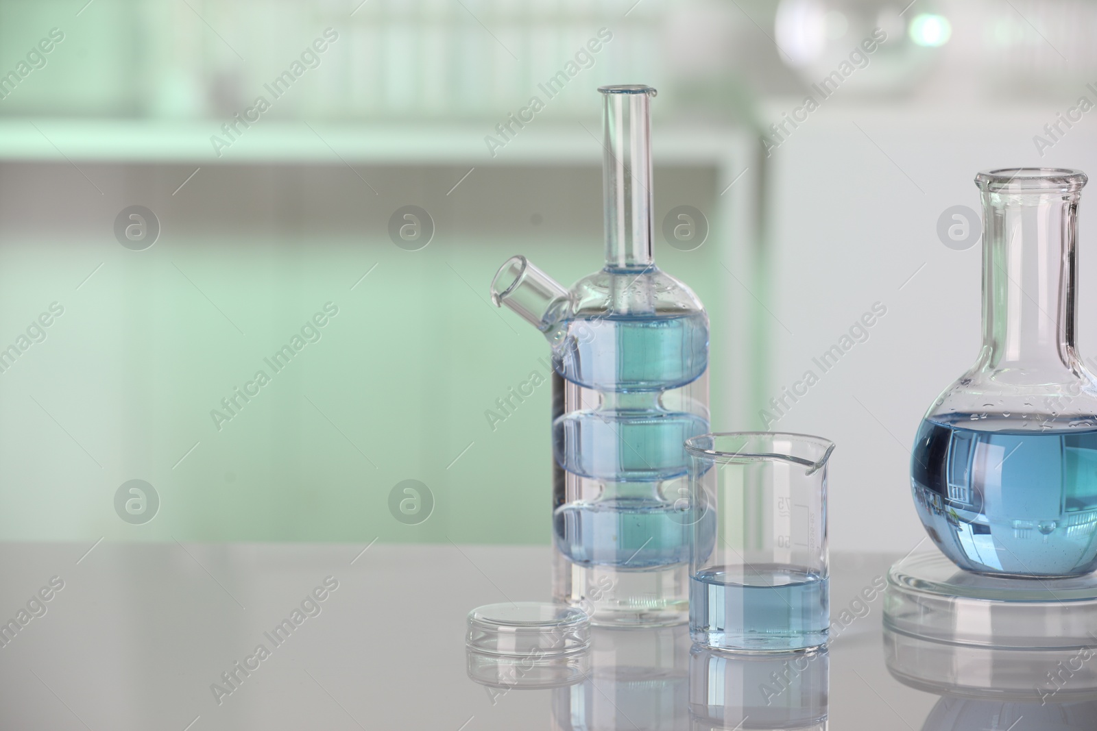 Photo of Laboratory analysis. Different glassware with liquid on white table indoors. Space for text