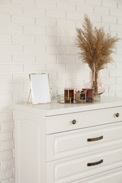 Modern chest of drawers with decor near white brick wall