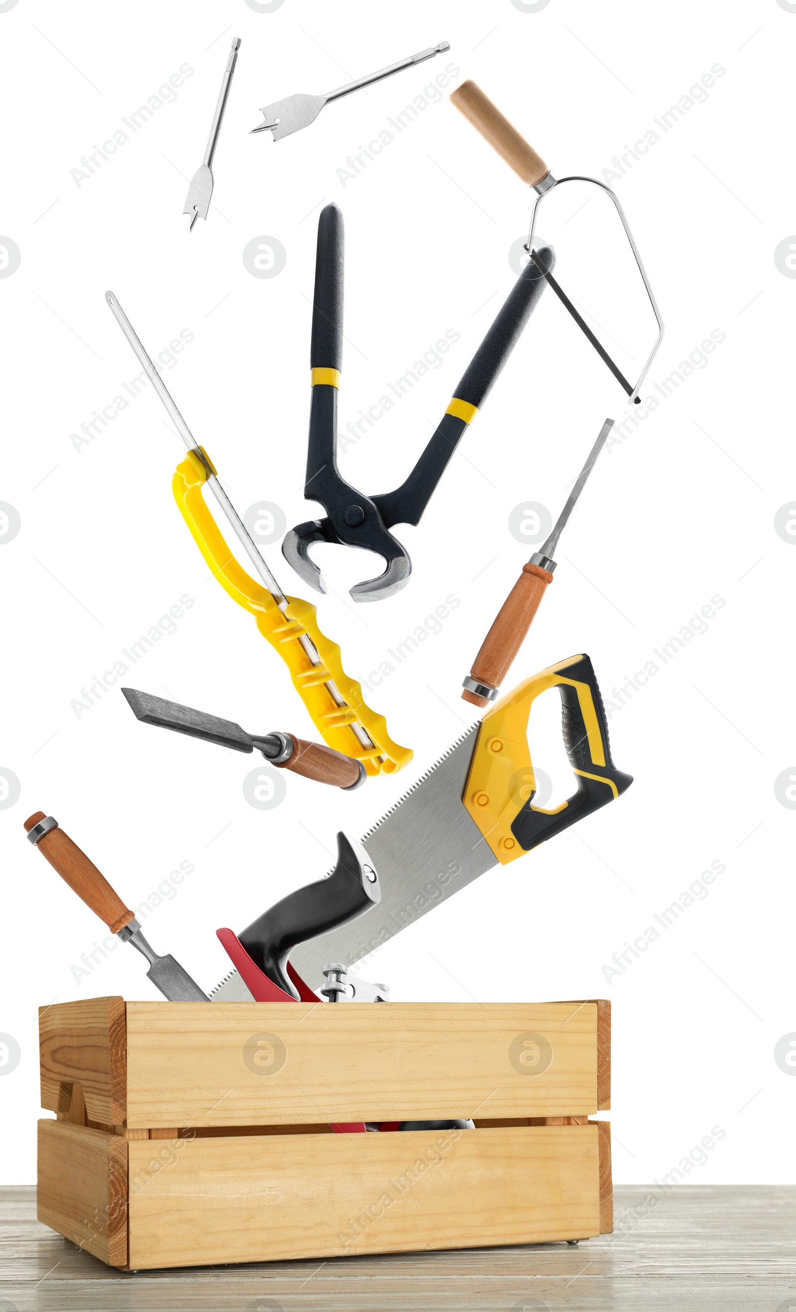 Image of Different carpenter's tools falling into wooden box on white background