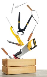 Different carpenter's tools falling into wooden box on white background