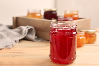 Photo of Jar with tasty sweet jam on wooden table
