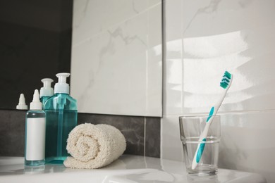 Photo of Light blue toothbrush, terry towel and cosmetic products in bathroom