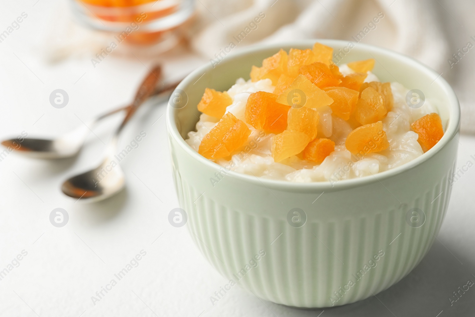 Photo of Delicious rice pudding with dried apricots on white table, closeup