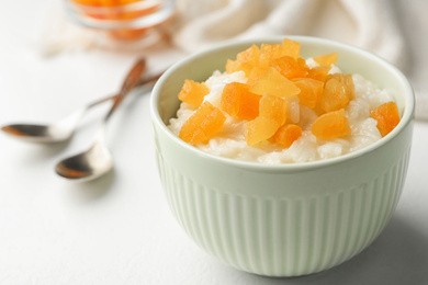 Photo of Delicious rice pudding with dried apricots on white table, closeup