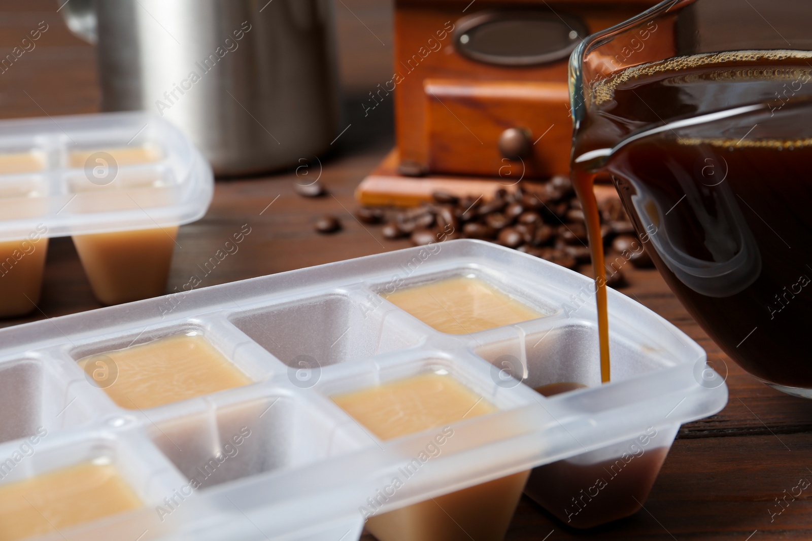 Photo of Pouring coffee in ice cube tray on table, closeup