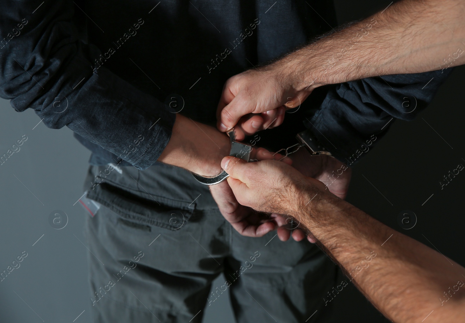 Photo of Man putting handcuffs on drug dealer, closeup view