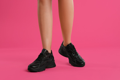 Woman wearing sneakers on pink background, closeup