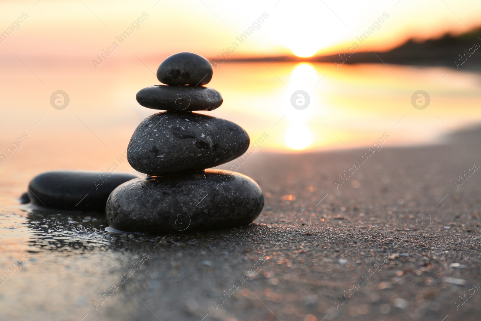 Photo of Dark stones on sand near sea at sunset, space for text. Zen concept