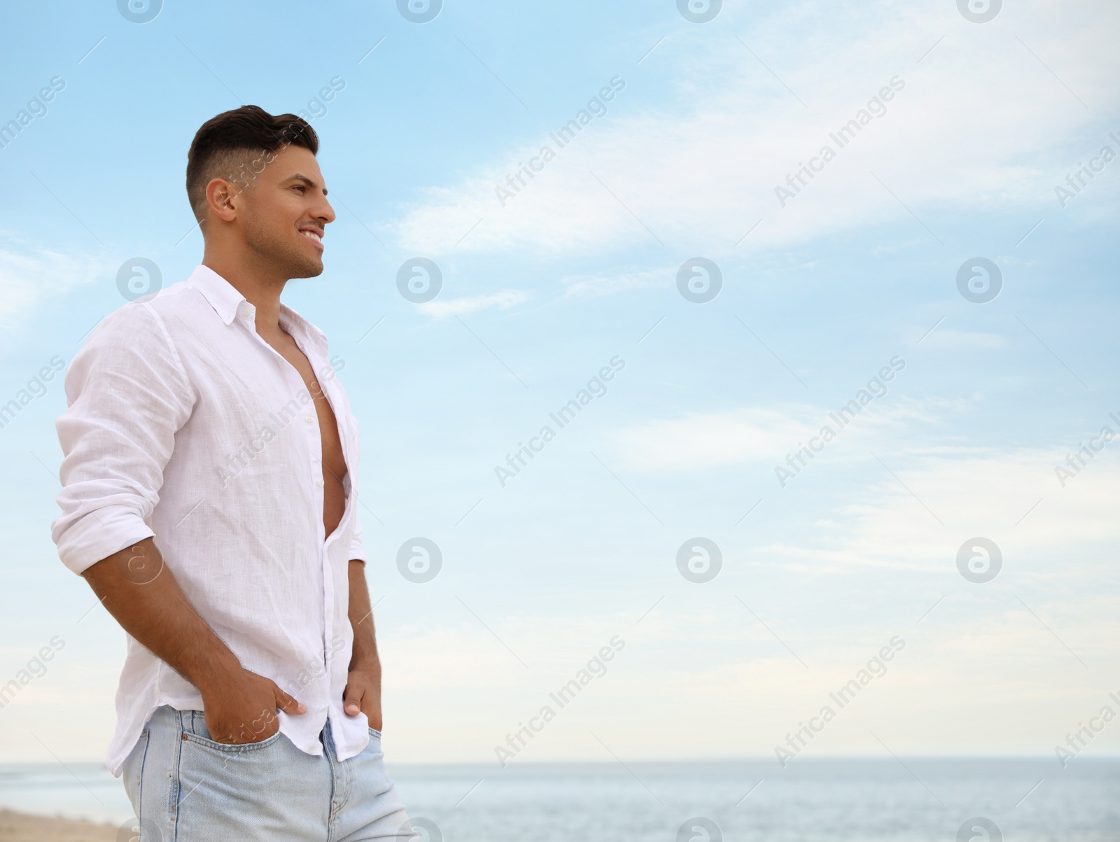 Photo of Handsome man on beach near sea. Space for text