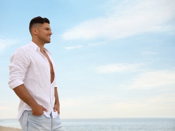 Handsome man on beach near sea. Space for text