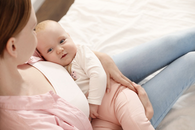 Young woman with her little baby resting after breast feeding on bed, above view