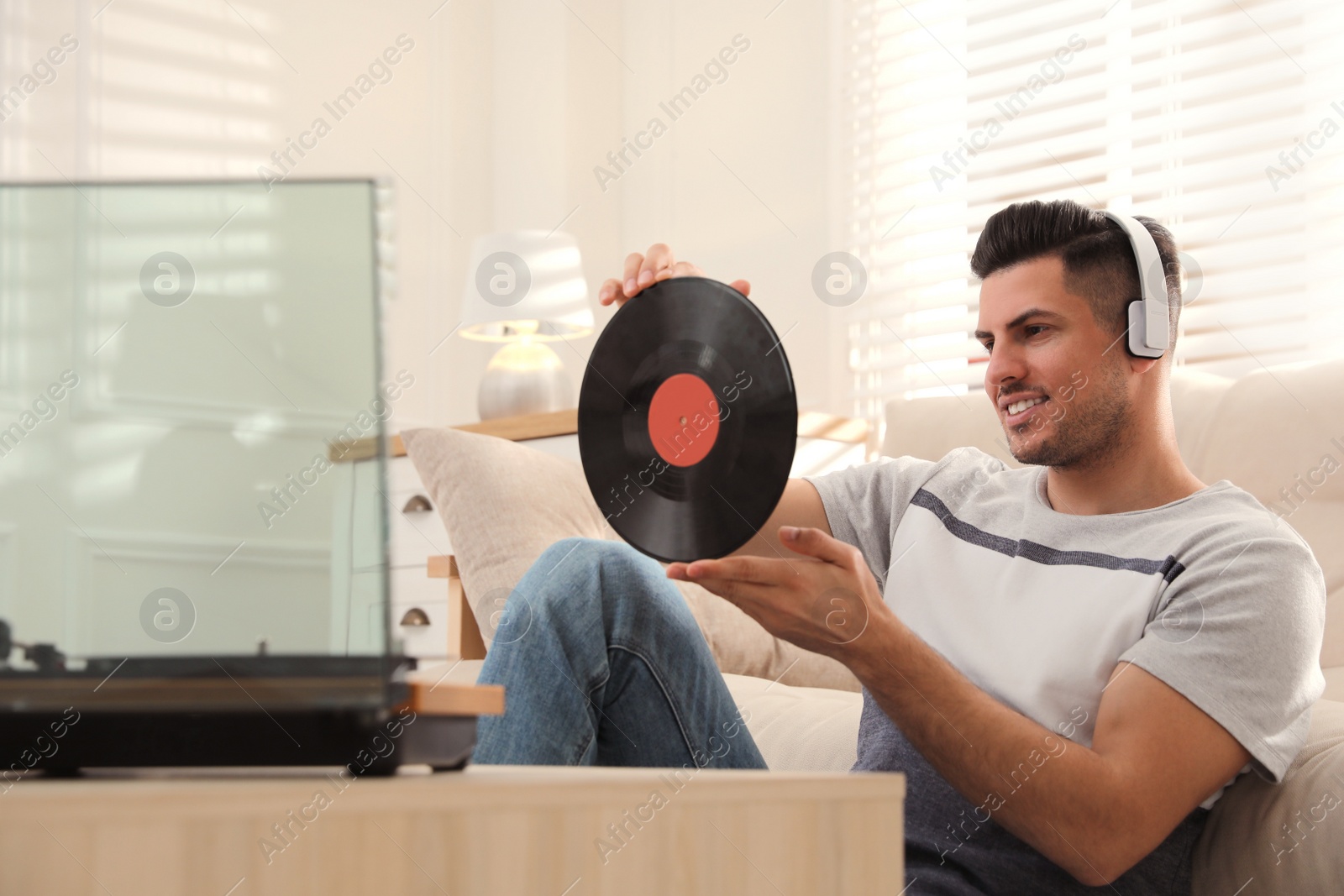 Photo of Happy man listening to music with turntable at home