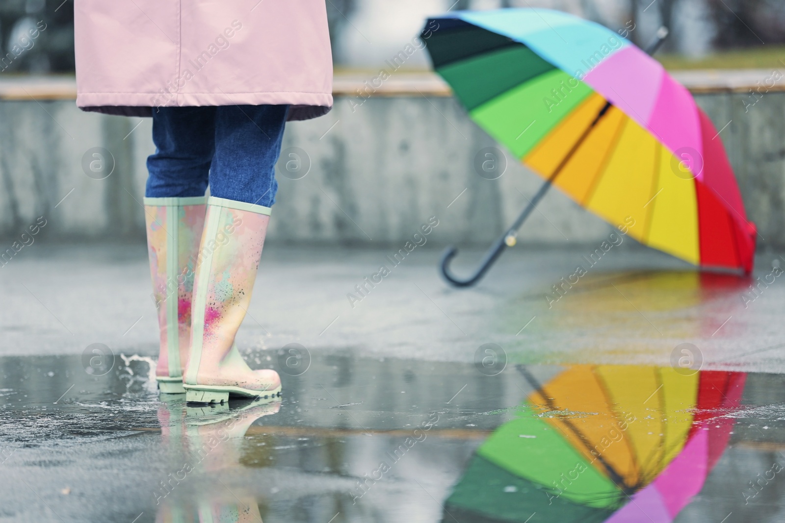 Photo of Woman in rubber boots walking outdoors on rainy day, closeup