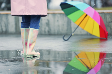 Woman in rubber boots walking outdoors on rainy day, closeup