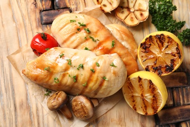 Photo of Grilled chicken breasts with garnish on wooden background, top view