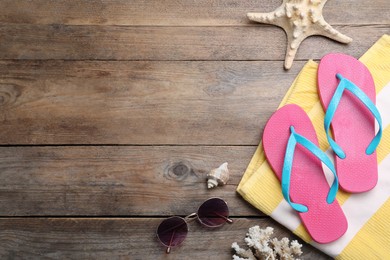 Photo of Stylish flip flops and beach objects on wooden background, flat lay. Space for text