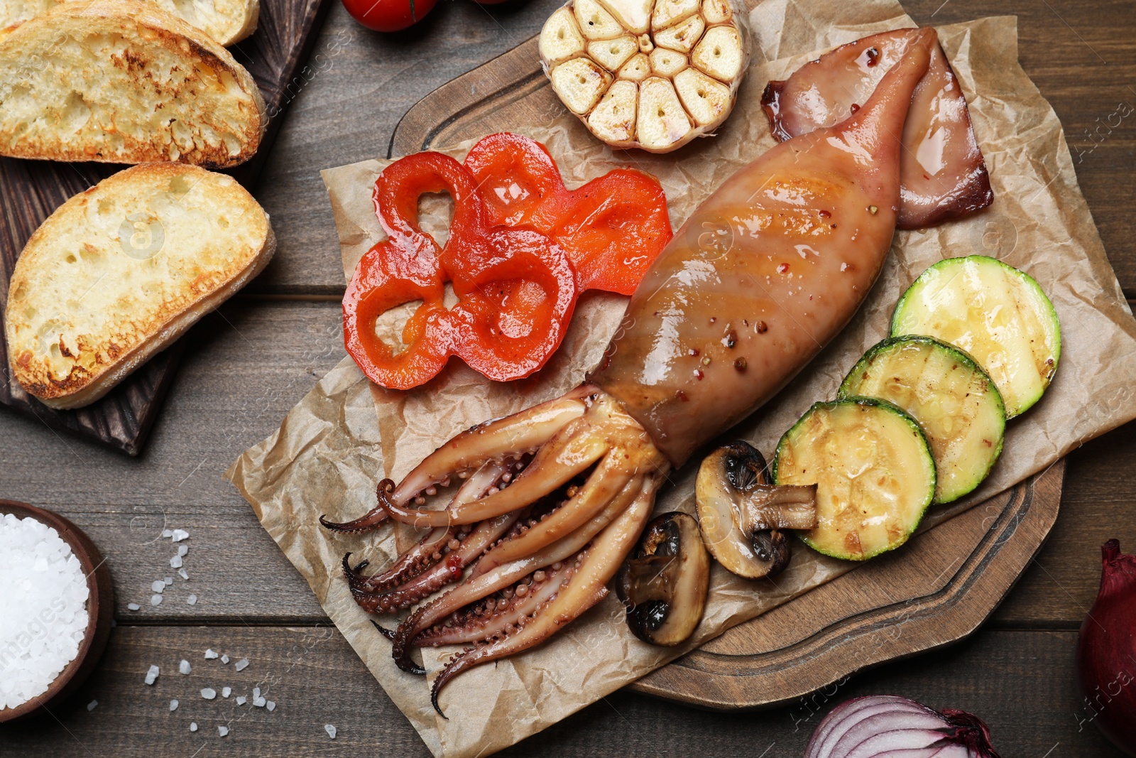 Photo of Tasty grilled squid served on wooden table, flat lay