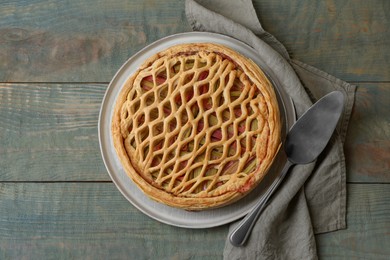 Photo of Freshly baked rhubarb pie and cake server on wooden table, flat lay