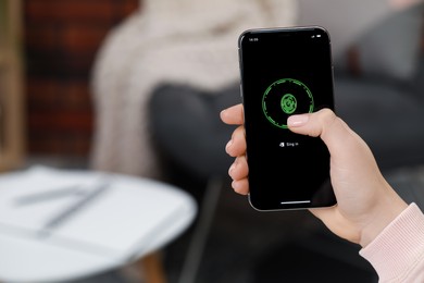 Woman unlocking smartphone with fingerprint scanner indoors, closeup. Space for text