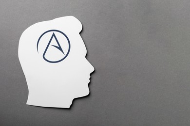 Image of Paper human head with symbol of atheism on grey background, top view. Space for text