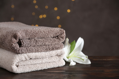 Photo of Stack of clean bath towels and beautiful flower on wooden table
