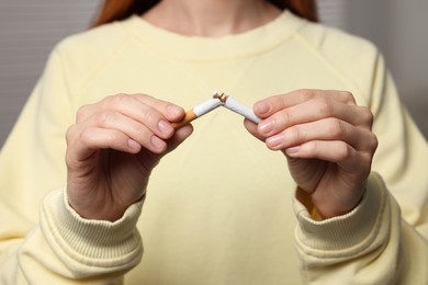 Photo of Stop smoking concept. Woman breaking cigarette on light gray background, closeup