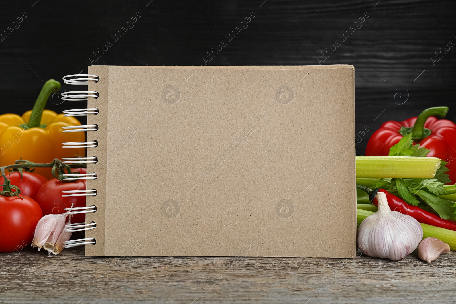 Photo of Blank recipe book and different ingredients on wooden table