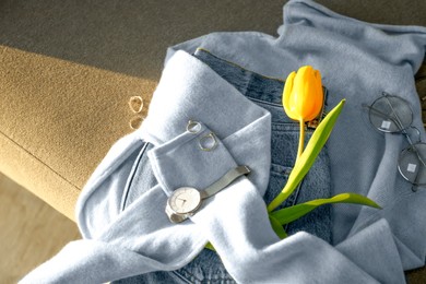 Photo of Soft cashmere sweater, jeans, accessories and tulip on sofa
