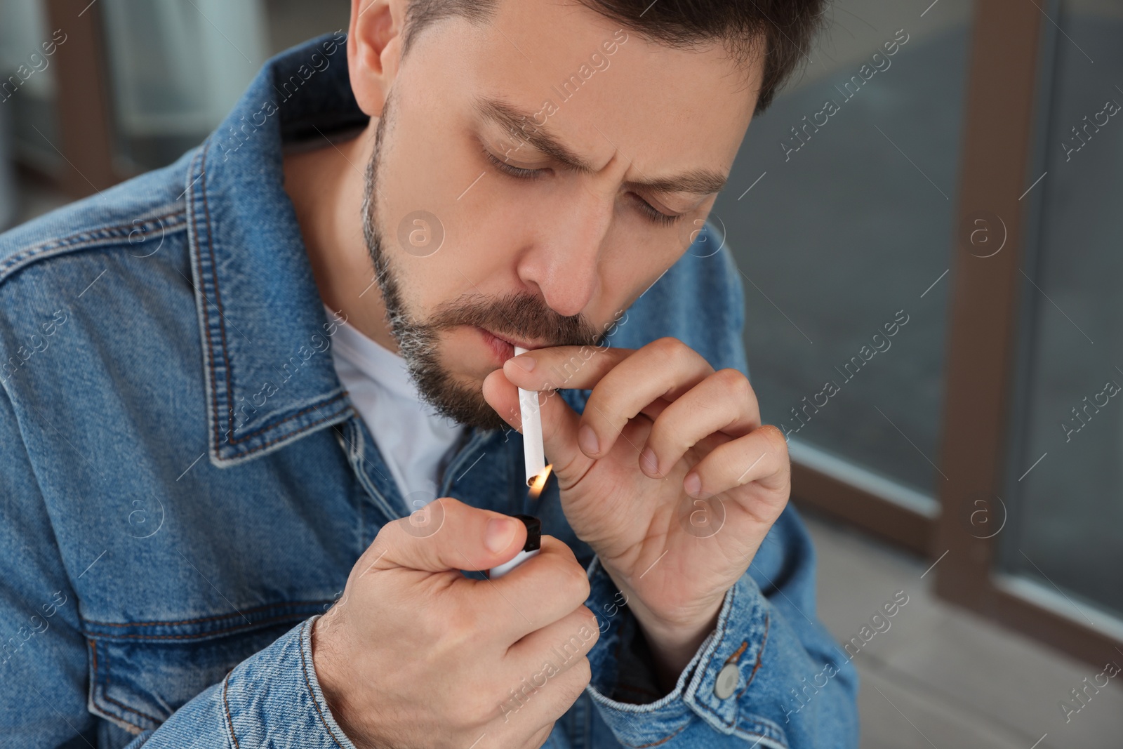 Photo of Mature man lighting cigarette outdoors, closeup of hands