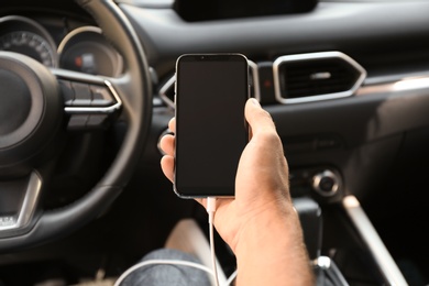 Photo of Man charging smartphone in car, closeup view
