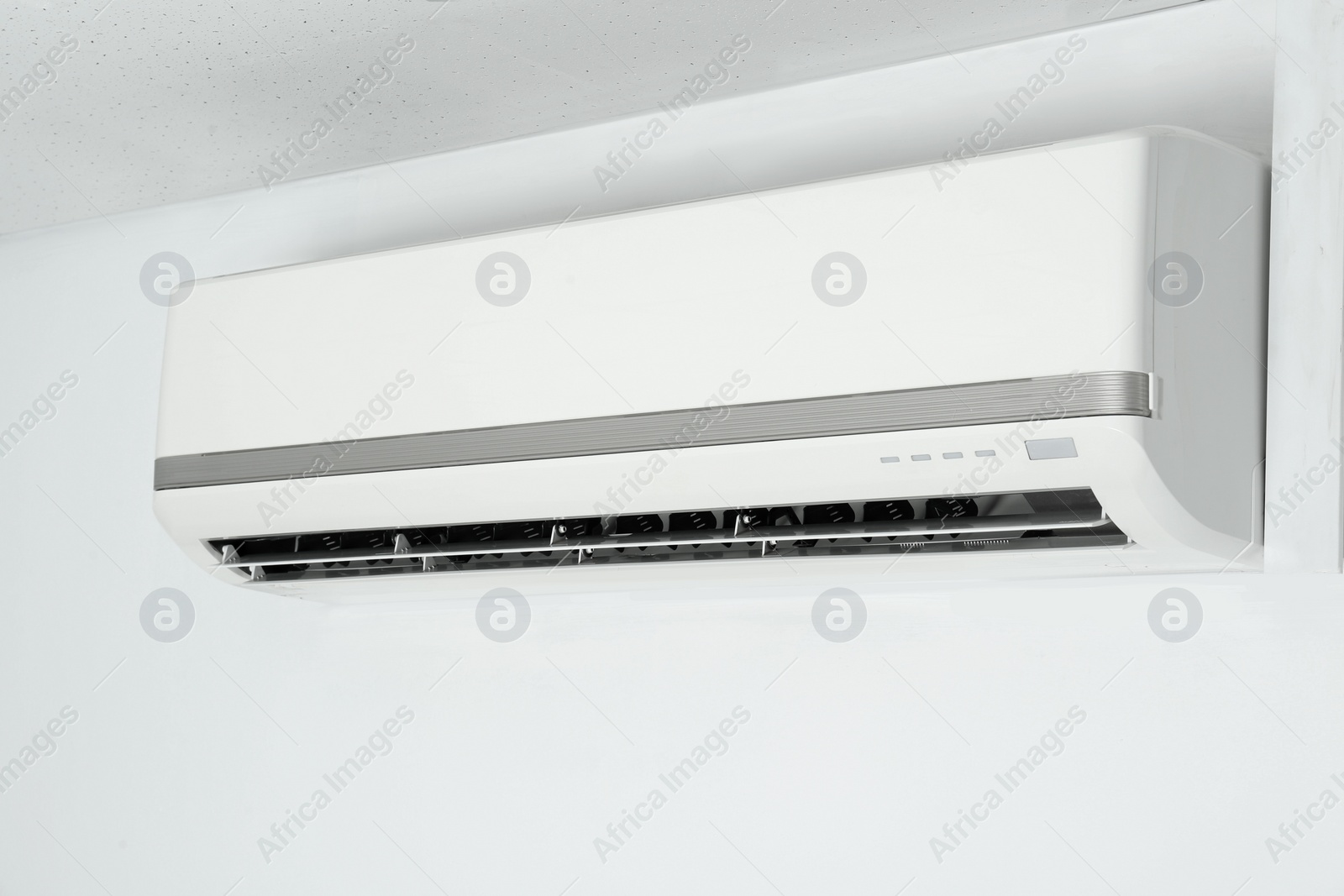 Photo of Modern air conditioner on white wall indoors