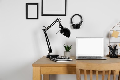 Photo of Home workplace. Laptop, lamp and stationery on wooden desk