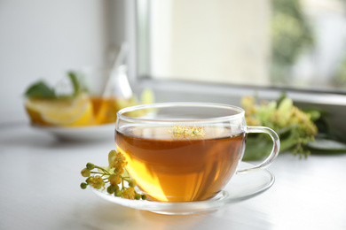 Photo of Cup of tea with linden blossom on white windowsill