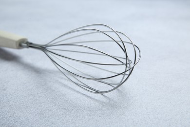 Metal whisk on gray table, closeup. Kitchen tool