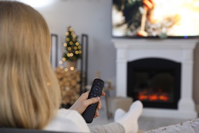 Woman watching TV in room decorated for Christmas