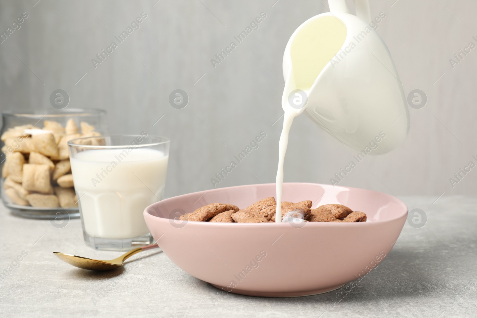 Photo of Pouring milk into bowl of tasty corn pads served for breakfast on light table