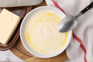 Photo of Bowl of delicious semolina pudding with butter served on table, top view