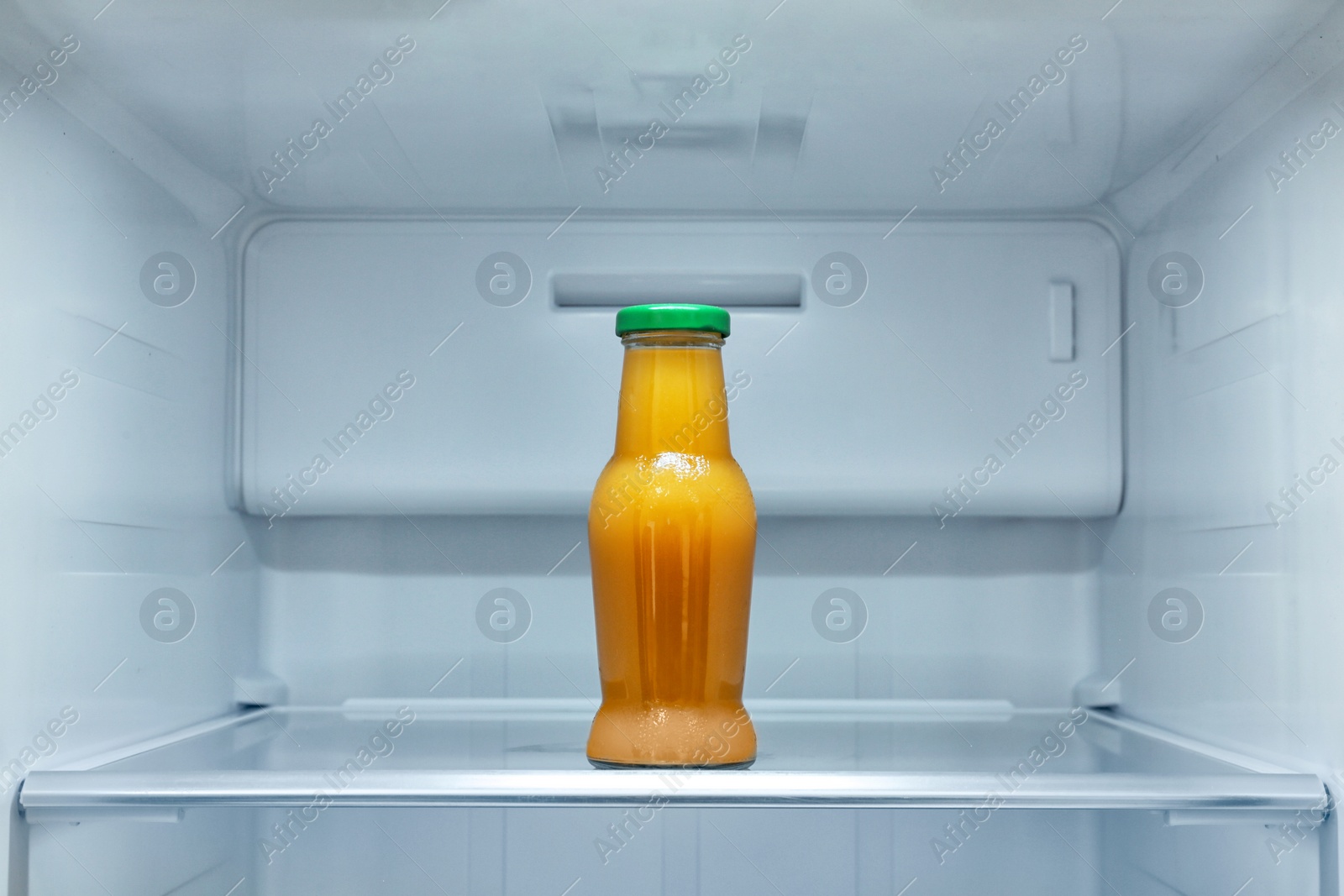 Photo of Bottle of juice on shelf in refrigerator