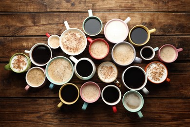 Many cups of different coffees on wooden table, flat lay