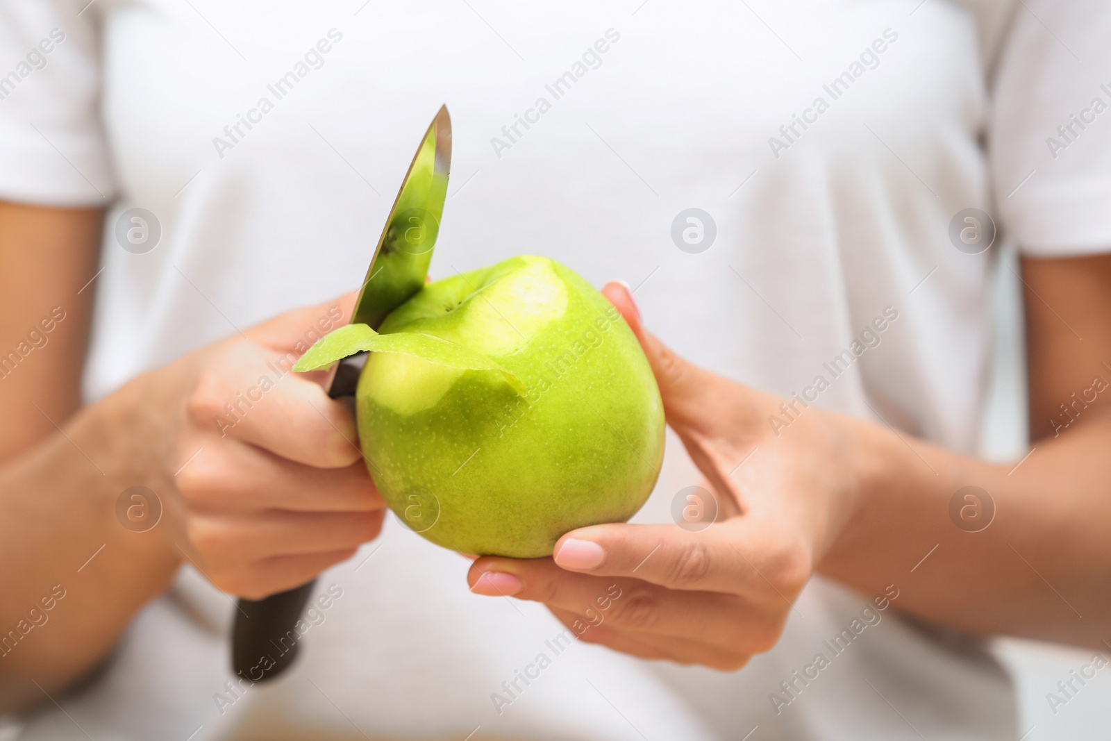Photo of Woman peeling fresh green apple, closeup view