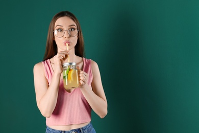 Photo of Emotional young woman drinking natural detox lemonade on green background. Space for text