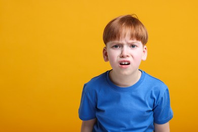 Photo of Portrait of surprised little boy on orange background, space for text