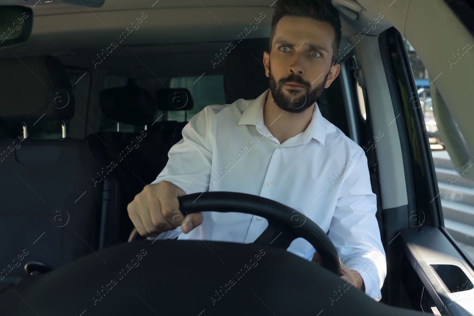 Photo of Stressed angry man in driver's seat of modern car, view through windshield