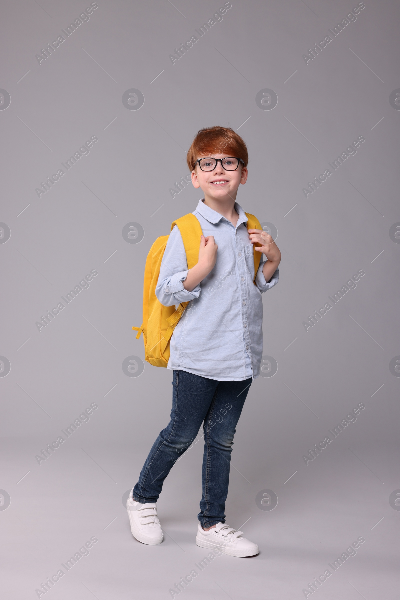 Photo of Happy schoolboy with backpack on grey background