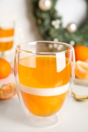 Photo of Delicious tangerine jelly in glass on white table, closeup