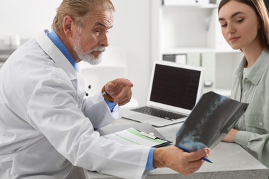 Photo of Orthopedist showing X-ray picture to patient in clinic