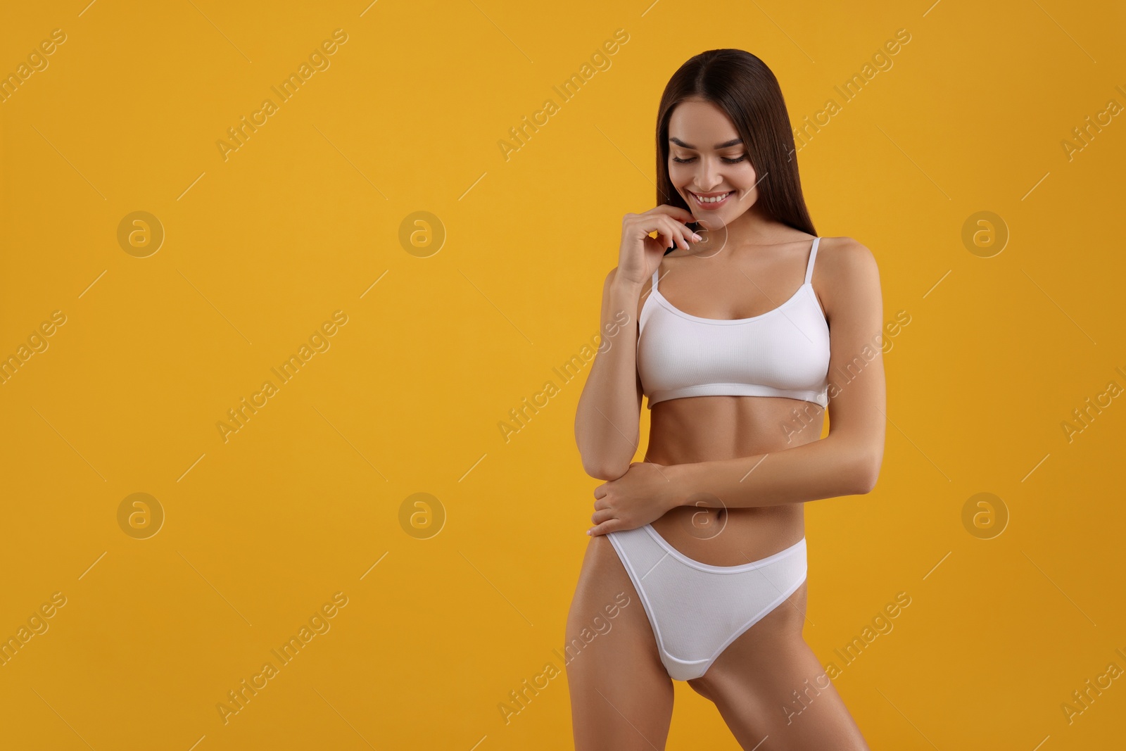 Photo of Young woman in stylish white bikini on orange background. Space for text