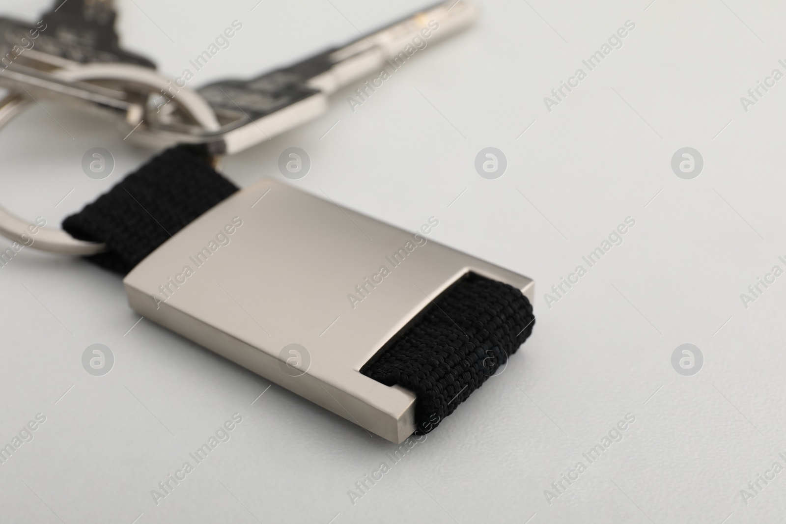 Photo of Keys with metal keychain on white marble table, closeup