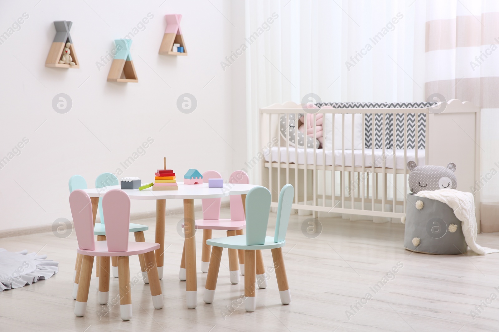 Photo of Cute baby room interior with cot and little table