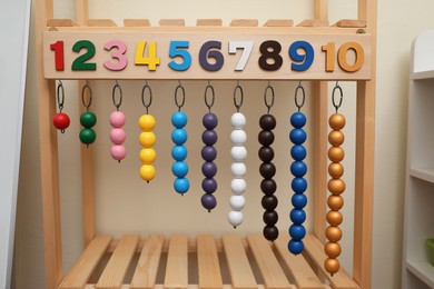 Photo of Montessori toy with color bead lines and numbers on wooden stand indoors